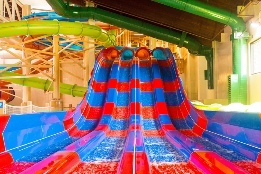 Two kids race down a waterslide laying on their stomaches 
